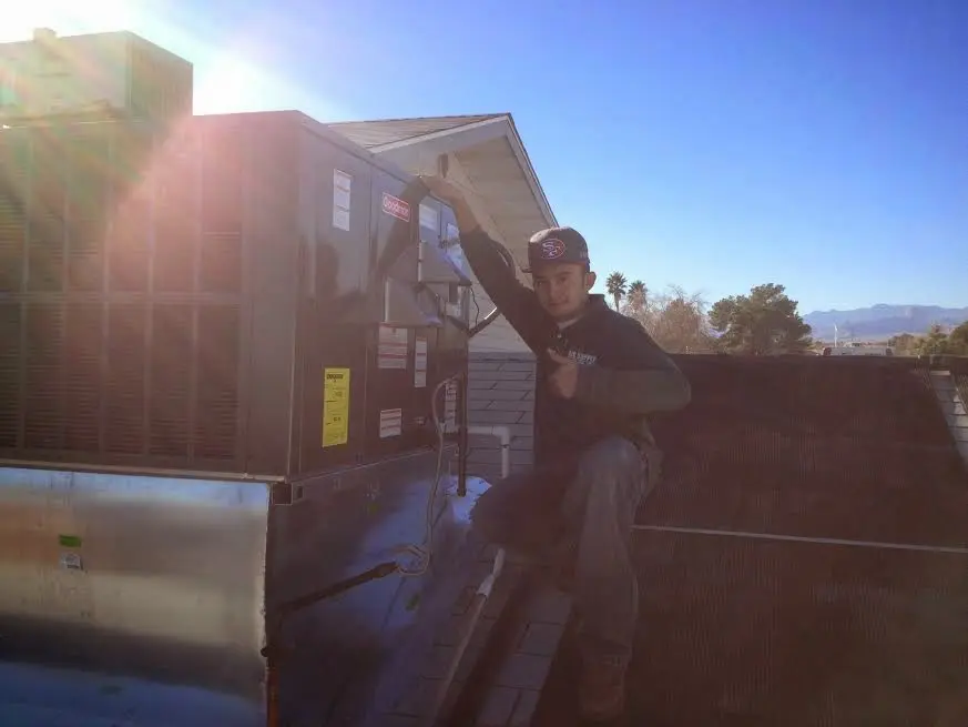 HVAC technician performing Air Duct Cleaning on a rooftop unit in New Canaan